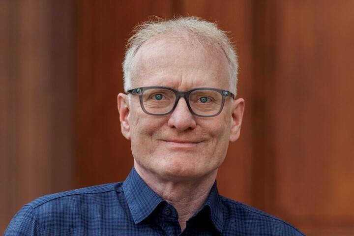 Matthias Kohring blickt direkt in die Kamera. Er hat eine Brille und trägt ein blau-kariertes Hemd