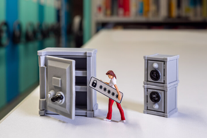 Auf dem Foto sieh man im Hintergrund die Archivschränke der Bibliothek, im Vordergrund befindet sich ein Miniaturtresor, in den eine Miniaturfigur ein Passwort legt. 