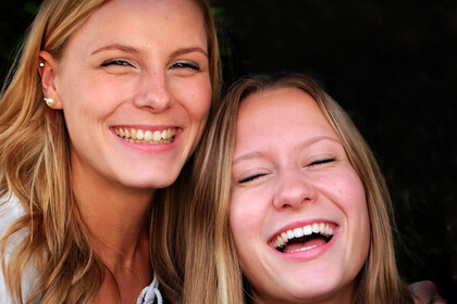 Zwei blonde Frauen Arm in Arm lachen freundlich
