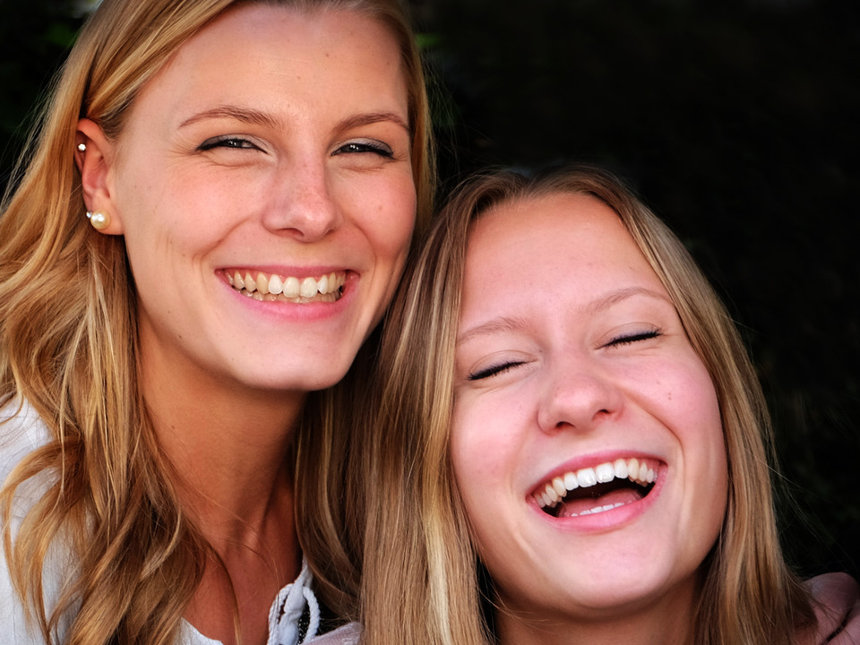 Zwei blonde Frauen Arm in Arm lachen freundlich