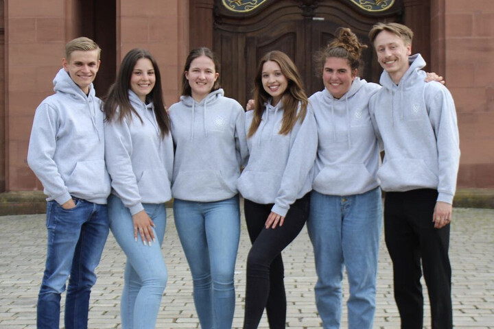 Die Studierenden der Fachschaft für Literatur- und Sprachwissenschaft steht lachend und mit grauen Pullis im Ehrenhof.