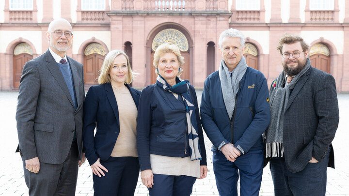 Fünf Personen stehen schick gekleidet nebeneinander auf dem Ehrenhof.