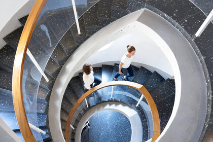 Zwei Studierende laufen eine Wendeltreppe der Universität Mannheim hoch.