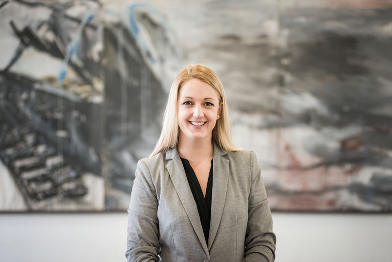 Portrait einer Frau mit Blazer vor einem Gemälde.