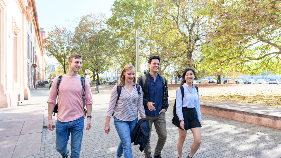 Four students are walking on a path in front of the castle, laughing