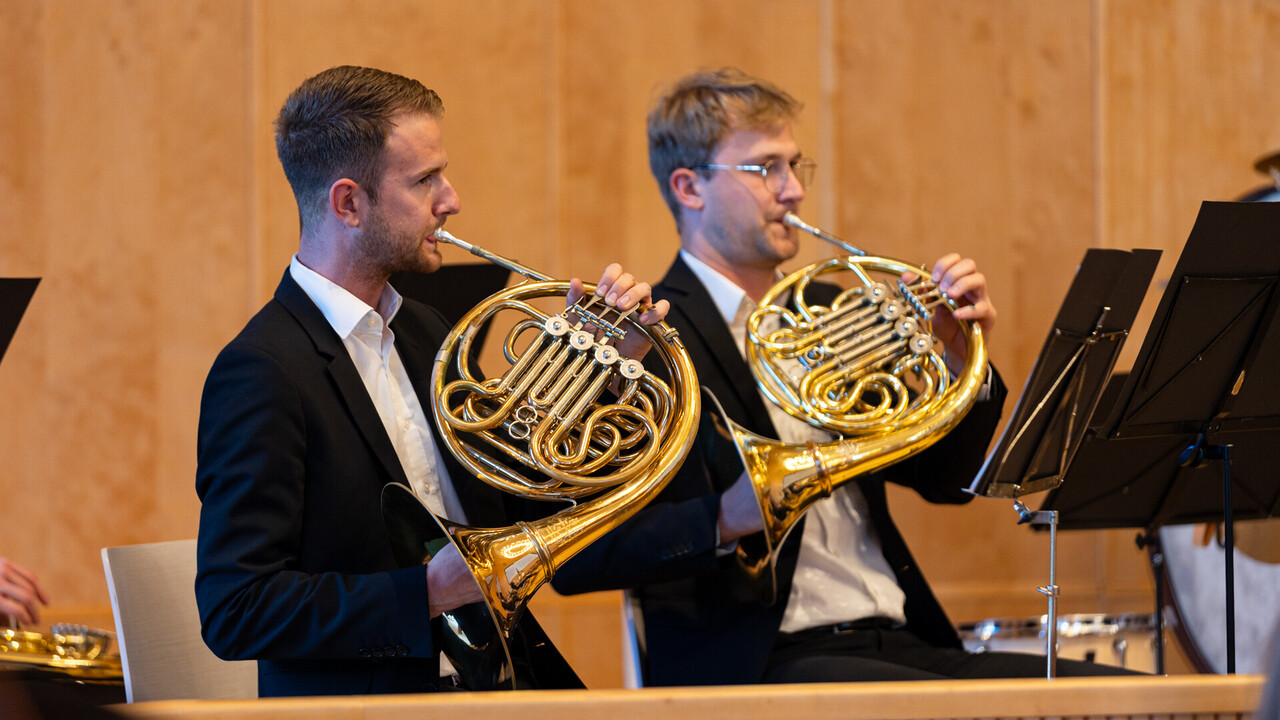 Auftritt des Unichors. Zwei Studierende sind schwarz gekleidet und spielen das Waldhorn.