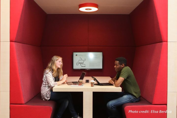 Eine Studentin und ein Student lernen gemeinsam in einer roten Nische im Learning Center der Universität Mannheim.
