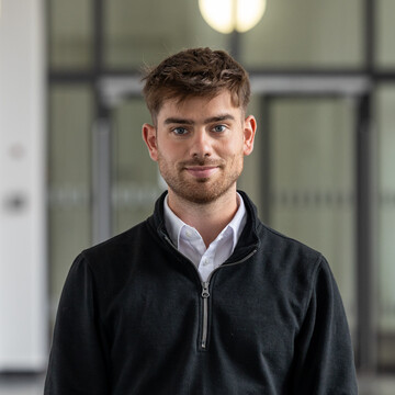 Luca di Leo wearing a white shirt and a black sweater.