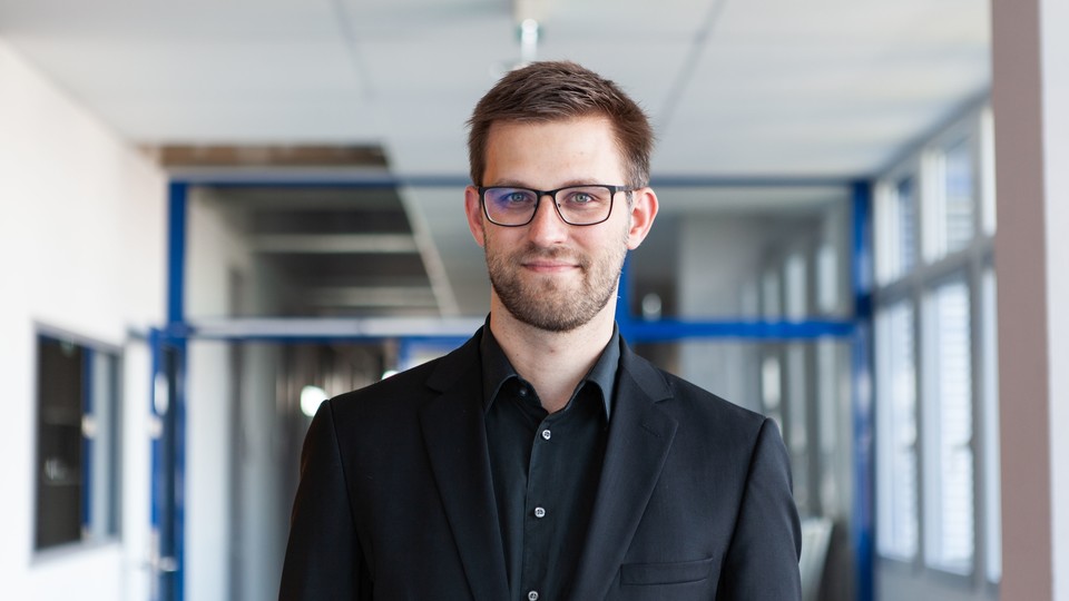 Dr. Stefan Janke hat kurze braune Haare, einen Bart und eine Brille. Er trägt ein schwarzes Jacket und ein schwarzes Hemd.