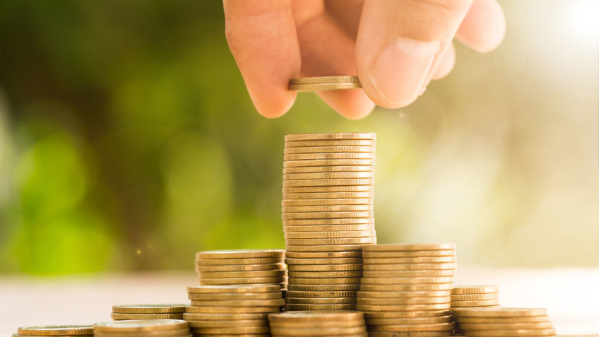 Eine Person stapelt Münzen aufeinander.
