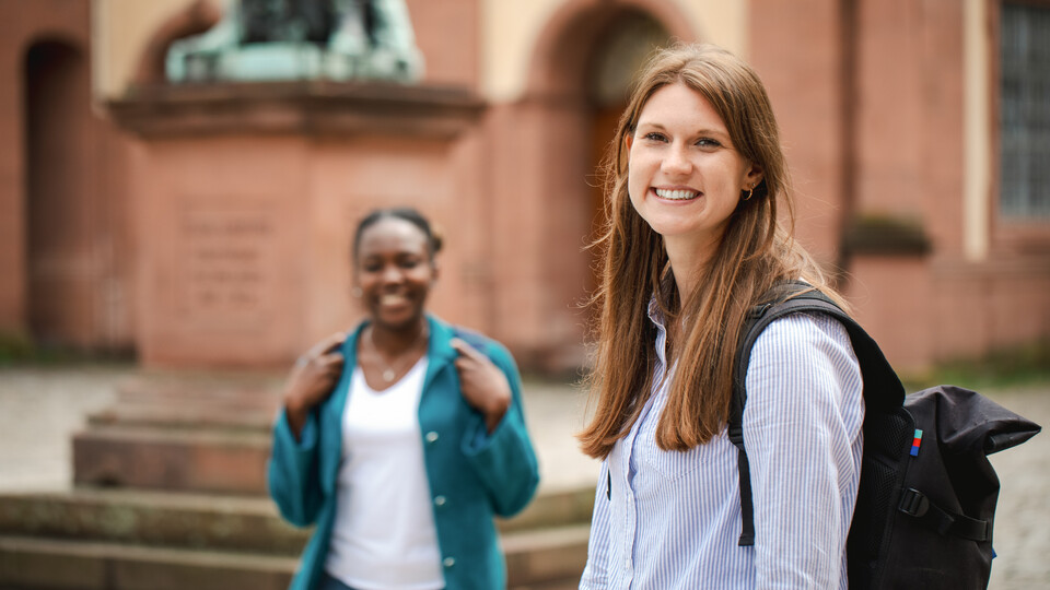 Zwei Frauen stehen auf dem Ehrenhof der Uni Mannheim und lachen.