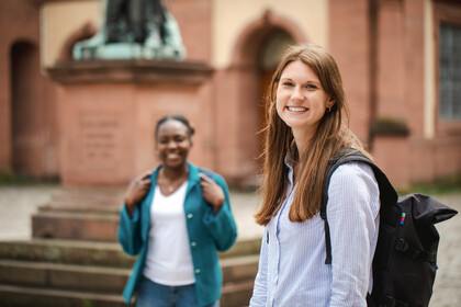Zwei Frauen stehen auf dem Ehrenhof der Uni Mannheim und lachen.