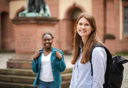Zwei Frauen stehen auf dem Ehrenhof der Uni Mannheim und lachen.
