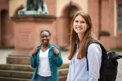 Zwei Frauen stehen auf dem Ehrenhof der Uni Mannheim und lachen.