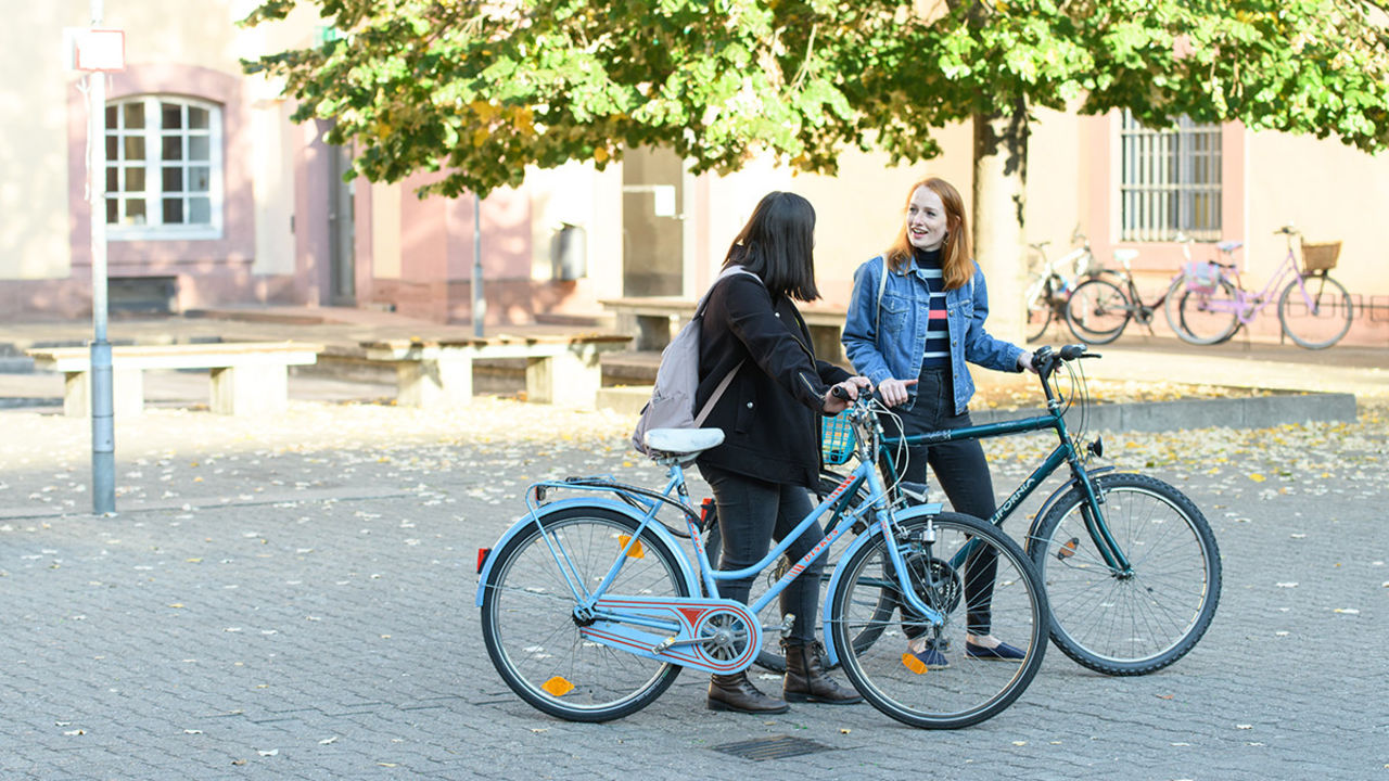 Zwei Studentinnen stehen mit ihren Fahrrädern im Schneckenhof