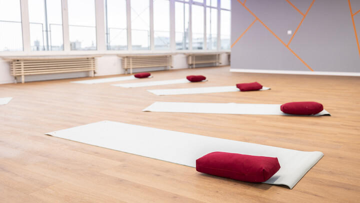 Yogastudio mit Matten und roten Yogakissen auf dem Boden ausliegend