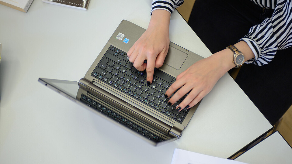 Zwei Hände einer Frau tippen auf einer Tastatur.