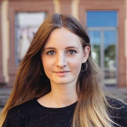 Fabia Gunkel hat braunes langes Haar, welches zu den Spitzen hin einen blonden Ton annimt. Sie hat dunkelblaue Augen und lächelt. Sie trägt ein schwarzes Sweatshirt und lächelt.