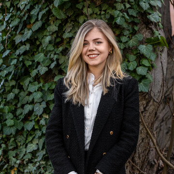 Nina Todorovic. Sie trägt einen schwarzen Anzug und lächelt.