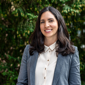 Karla Funes. Karla Funes lächelt und trägt einen blauen Blazer sowie eine weiße Bluse.