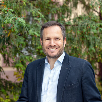 Lutz Pöhlmann. Er lacht und trägt ein dunkles Jackett.