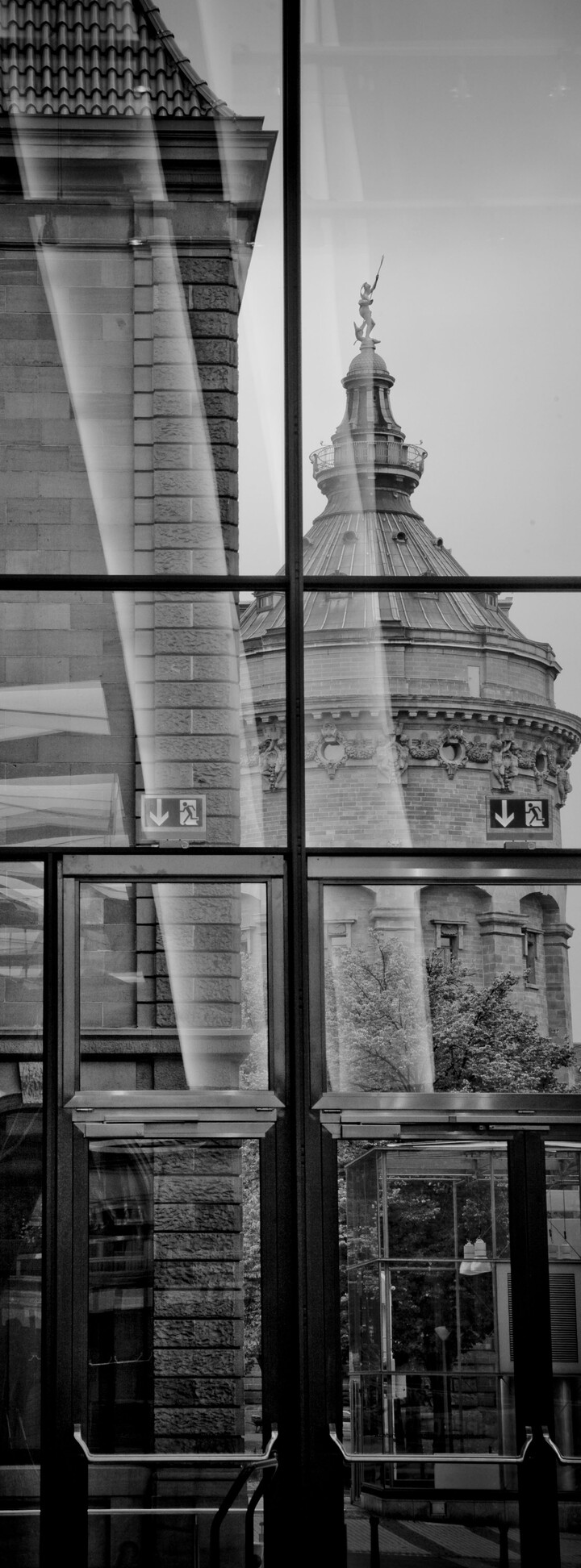 Schwarz-weiß Foto innerhalb eines Gebäudes mit Fensterfront und Blick auf den Mannheimer Wasserturm.