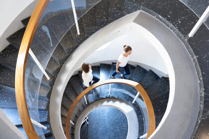 Blick auf Wendeltreppe Schneckenhof von oben, zwei Studierende laufen die Treppe hoch